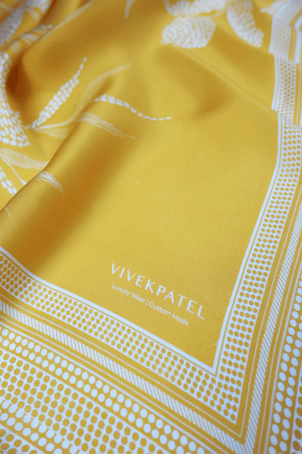 Yellow scarf with white floral patterns and 'Vivek Patel' branding
